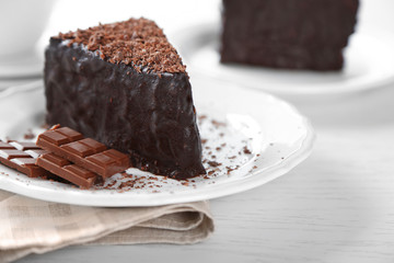 Chocolate cake with chocolate cream on plate, on light background
