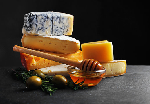 Different kinds of cheese, honey and olives on the table, close up