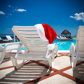Santa Claus Hat on Lounge sunbeds near swimming pool