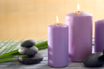 Fototapeta na wymiar Purple candles with spa stones and bamboo on table