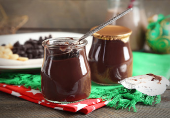 Chocolate dessert in a small glass jars and chocolate milk cocktail on wooden background