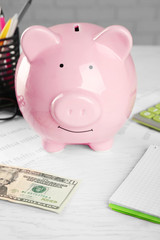 Bookkeeping concept. Piggy bank, calculator, dollars and papers on white wooden background