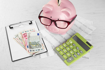 Bookkeeping concept. Piggy bank, calculator, euro and papers on white wooden background