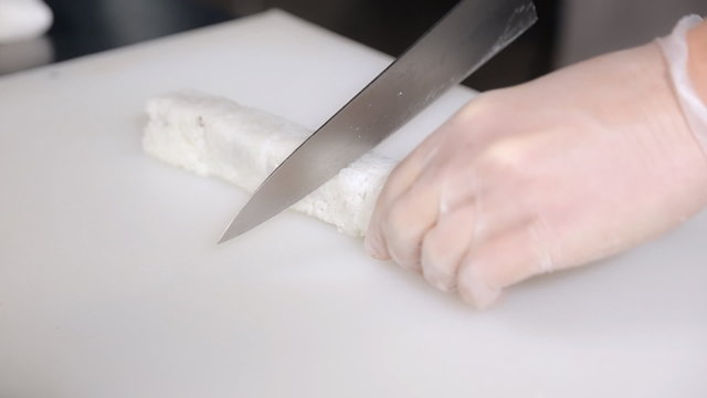 cooking sushi rolls in the studio. cut into portions, the master hands in gloves with a knife.