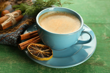 Cup of coffee with sweet spices on napkin on green wooden background