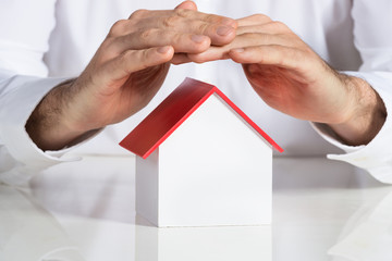 Businessman Protecting House Model At Office Desk