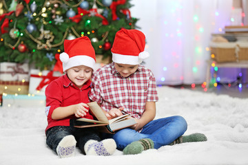 Fototapeta na wymiar Two cute small brothers reading book on Christmas decoration background