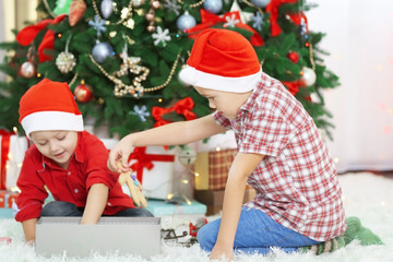 Obraz na płótnie Canvas Two cute small brothers opening gifts on Christmas decoration background