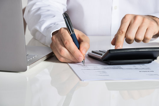 Businessman Calculating Invoice By Laptop