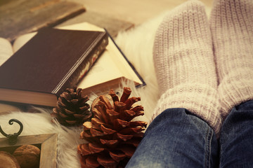 Woman legs, pine cone and books, closeup