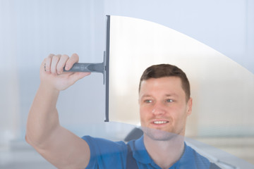 Worker Cleaning Glass Window With Squeegee