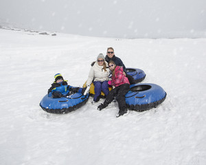 Fototapeta na wymiar Family Sledding and playing in snow together. Having fun on a snowy day