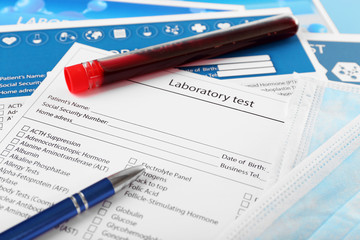 Blood in test tubes, pen and investigation form on the table, close-up