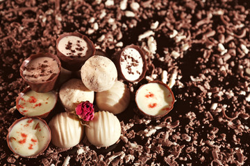 Assorted chocolate candies with flakes on black background