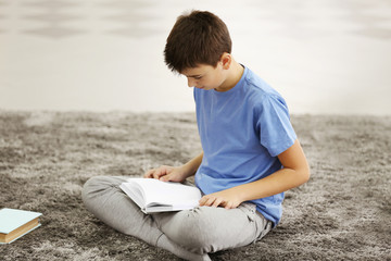 Naklejka na ściany i meble Boy reading books on a floor at home