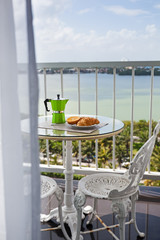 Breakfast with coffee on balcony, overlooking view with curtains