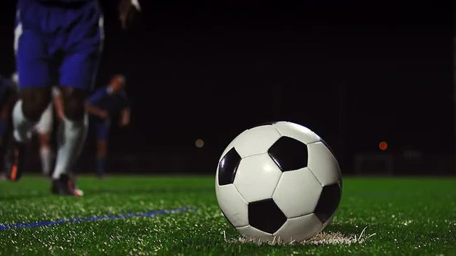 Close up of a soccer ball being kicked in slow motion at night