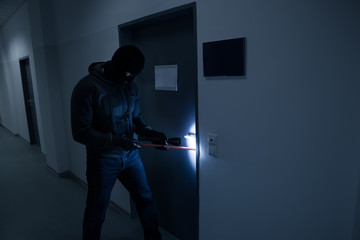 Thief With Flashlight Trying To Break Office Door