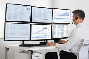 Fototapeta na wymiar Stock Market Broker Looking At Graphs On Multiple Screens