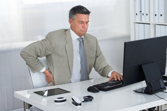 Mature Businessman Suffering From Back Pain At Desk