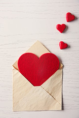 Blank open envelope with hearts on wooden background