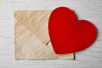 Blank envelope with heart on wooden background