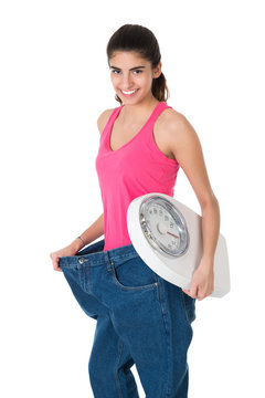 Smiling Woman With Weight Scale Showing Her Old Jeans