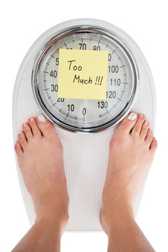 Woman Standing On Weight Scale With Too Much Note