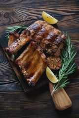 Baked pork ribs served on a wooden chopping board, closeup