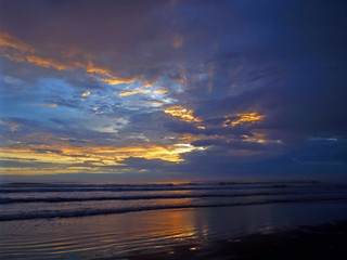 Cloudy Sunset Over the Ocean with Waves in the Foreground