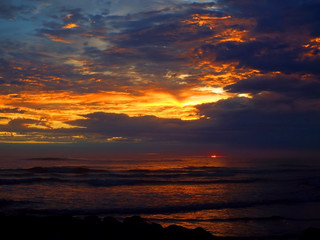Cloudy Sunset Over the Ocean with Waves in the Foreground
