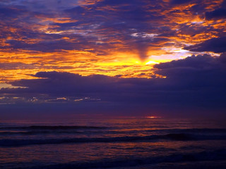 Cloudy Sunset Over the Ocean with Waves in the Foreground