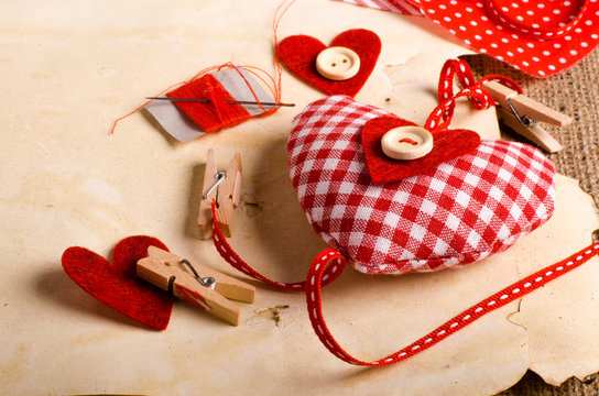 Sewing set: fabrics, threads, pins, buttons, tape and handmade hearts on vintage paper background. Retro design effects.