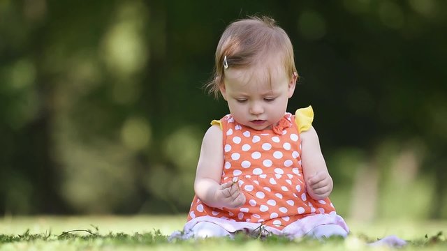 happy newborn baby playing with grass in park at beautiful sunny day