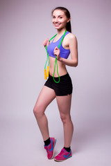Naklejka premium Young fitness woman with healthy sporty figure with skipping rope