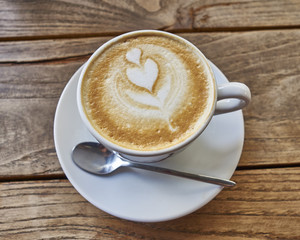 Cup of hotlatte art coffee on wooden table