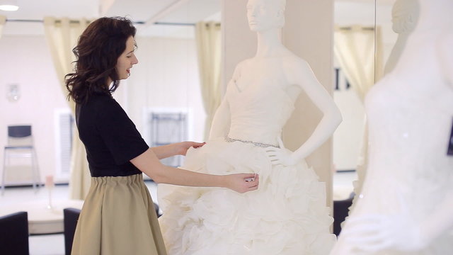 woman chooses wedding gown at bridal boutique
