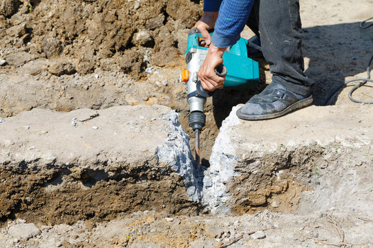 Worker hammer smashes the concrete foundation