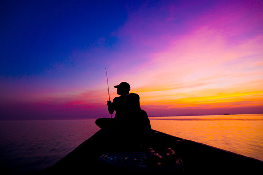Lonely man fishing silhouettes on sunset sky beautiful lagoon