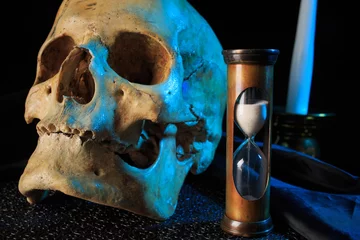 Fotobehang Oude meesters human skull on a book next to the clock. concept of black magic  © kopitinphoto