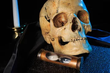Fotobehang Oude meesters human skull on a book next to the clock. concept of black magic  © kopitinphoto