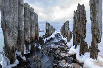 Fototapeta na wymiar Frozen wooden breakwaters line to the world war II torpedo platform at Baltic Sea, Babie Doly, Poland