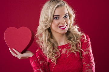 Smiling woman holding red heartshape box.