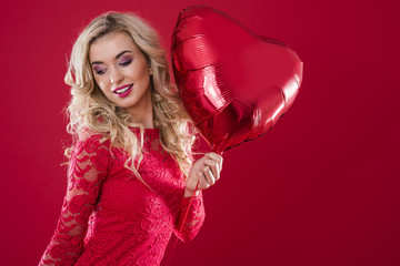 Big red heartshape balloon held by cheerful woman