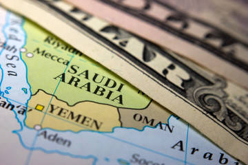 Fototapeta na wymiar Dollar bills on top of a map of Arabia