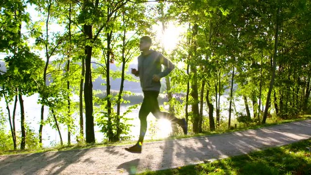 Young man running in park during sun rise slow motion