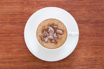 A cup of cappuccino at the wooden table