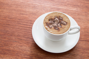 A cup of cappuccino at the wooden table