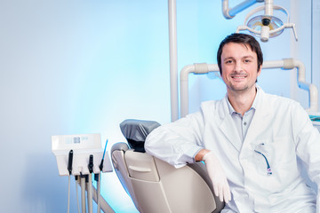 Zahnarzt  lächelt in die Kamera auf dem  Stuhl in der Zahnklinik 