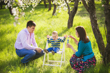 Father, mother and child playing together outside blowing soap bubbles